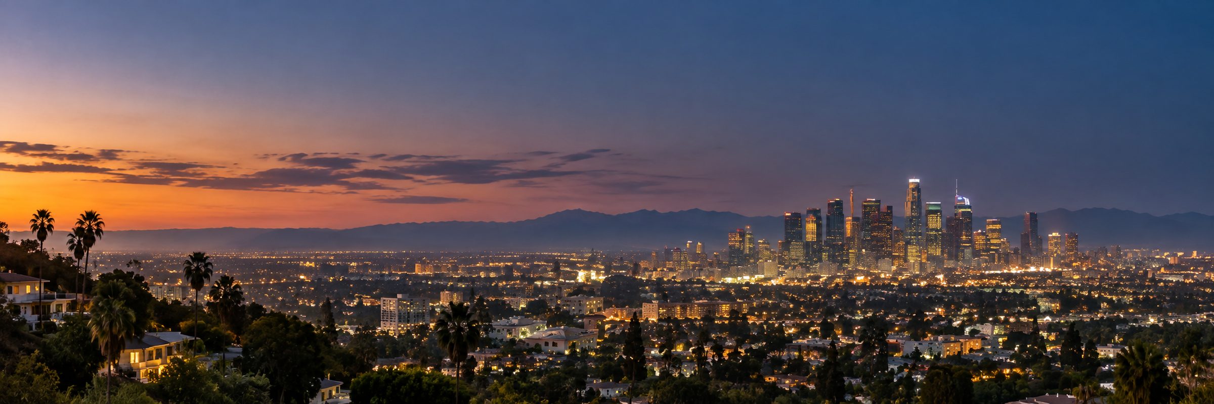 The Los Angeles basin at dusk, with the downtown skyline lit against the San Gabriel Mountains
